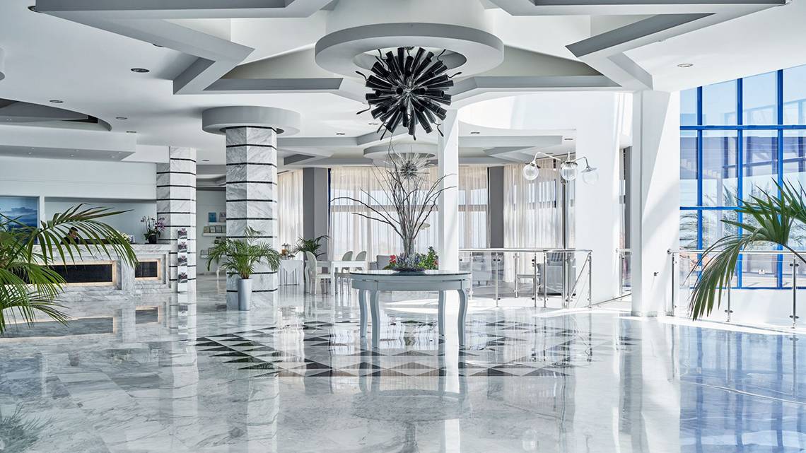 Lobby des Rodos Princess Beach Hotels mit Marmorboden, modernen Möbeln und Pflanzen.