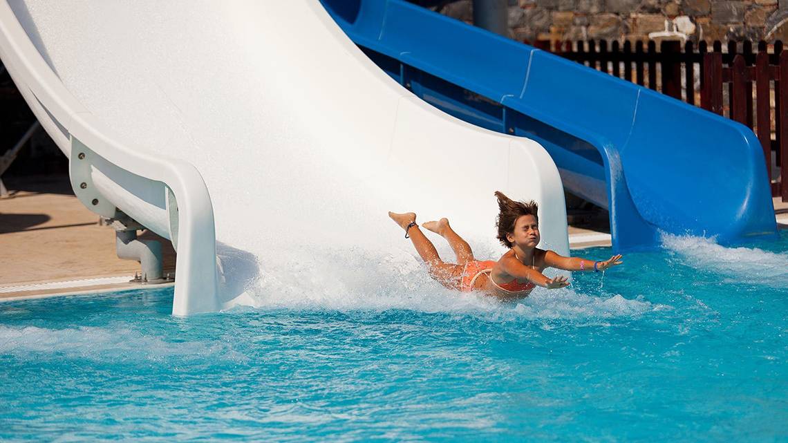 Mädchen rutscht von einer weißen Rutsche in den Pool im Rodos Princess Beach Hotel.