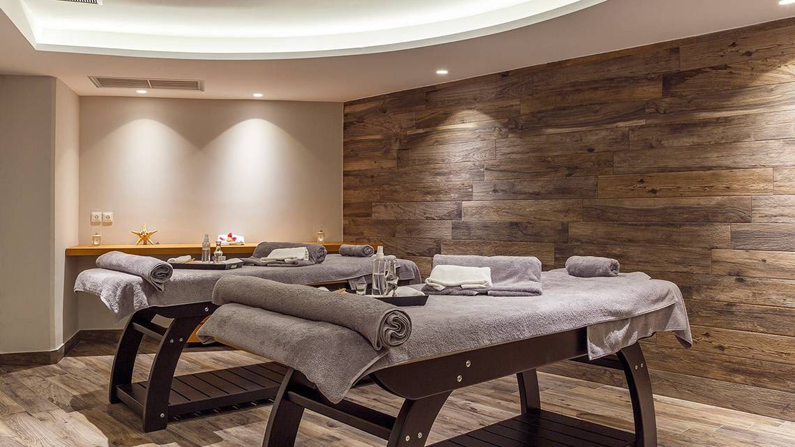 Massagebereich im Rodos Princess Beach Hotel mit zwei Massagetischen und Holzwänden.