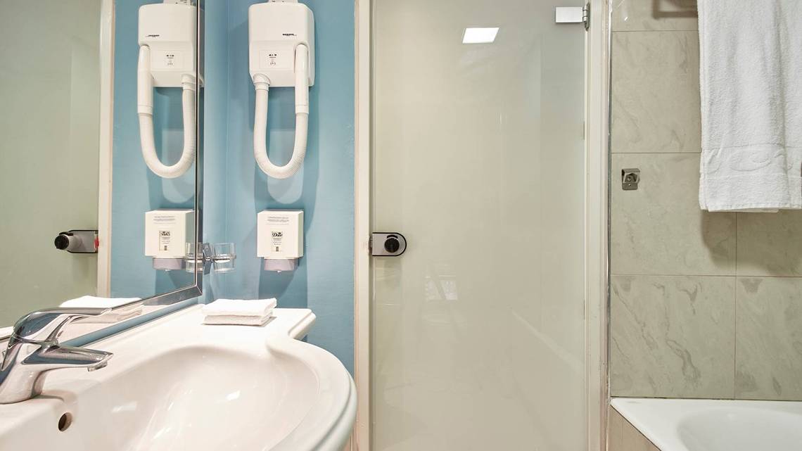 Badezimmer im Esperides Beach Resort mit Waschbecken, Spiegel und Dusche.