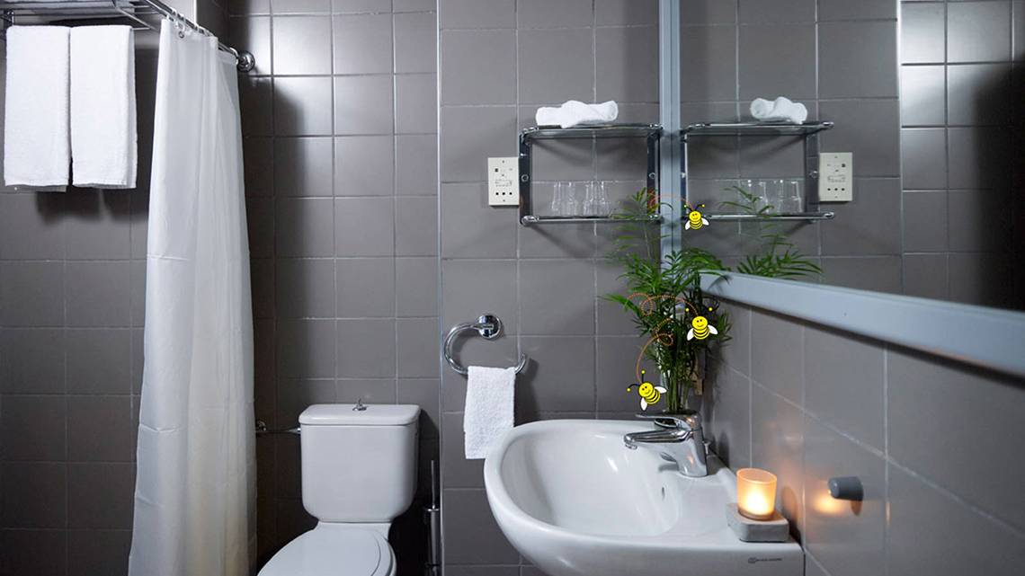 Badezimmer im Esperides Beach Resort mit grauen Fliesen, einer Toilette, einem Waschbecken und Handtüchern