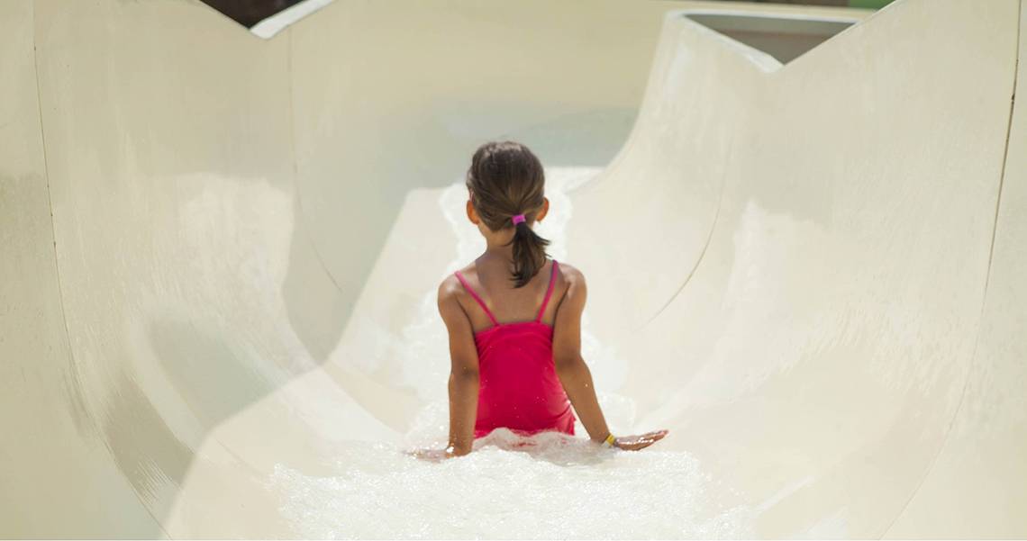 Kleines Mädchen rutscht in einer weißen Wasserrutsche des Esperides Beach Resorts