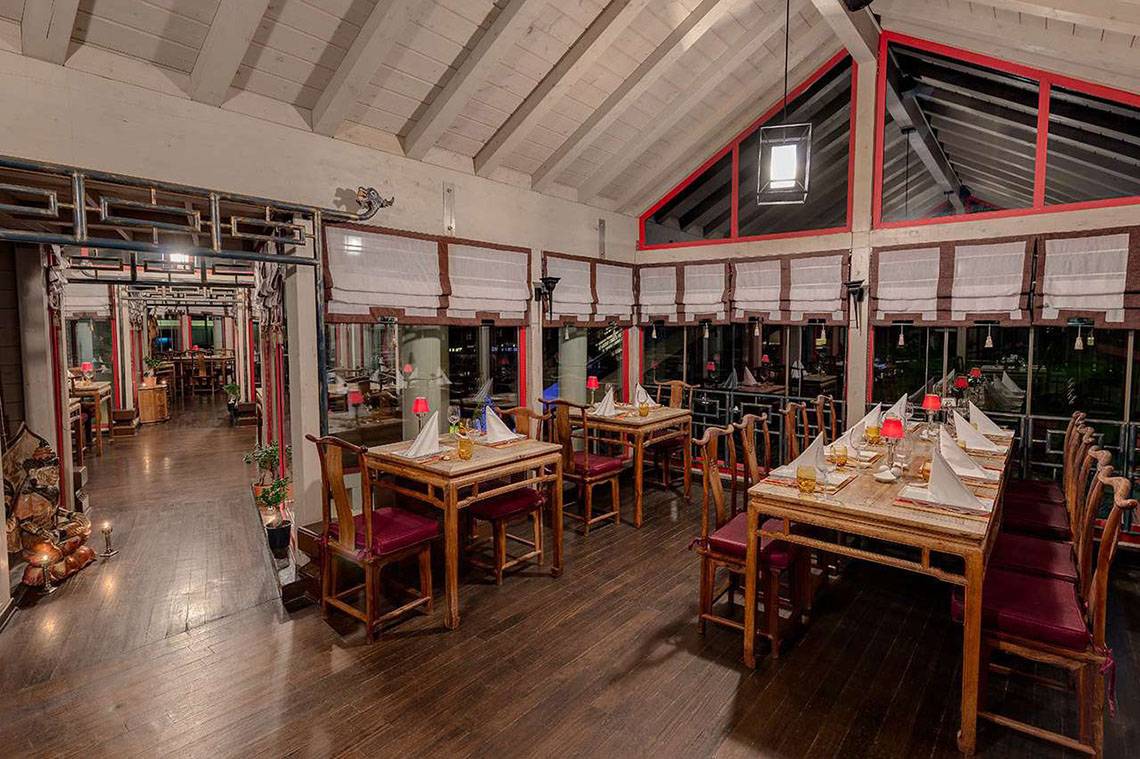 Innenbereich des Susesi Luxury Resorts Restaurants mit Holztischen und roten Stühlen.
