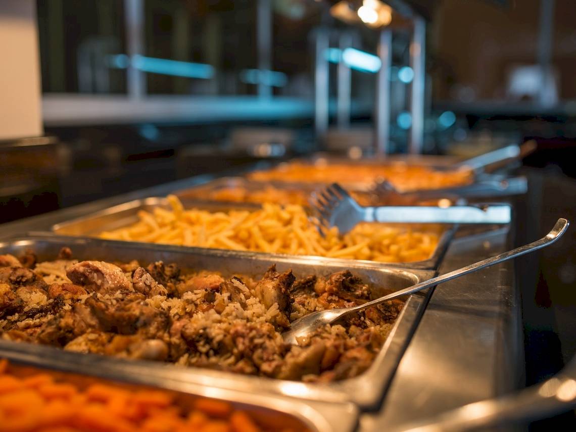 Buffet-Tisch im Astir Palace Hotel mit verschiedenen Gerichten wie Fleisch, Reis und Pommes.
