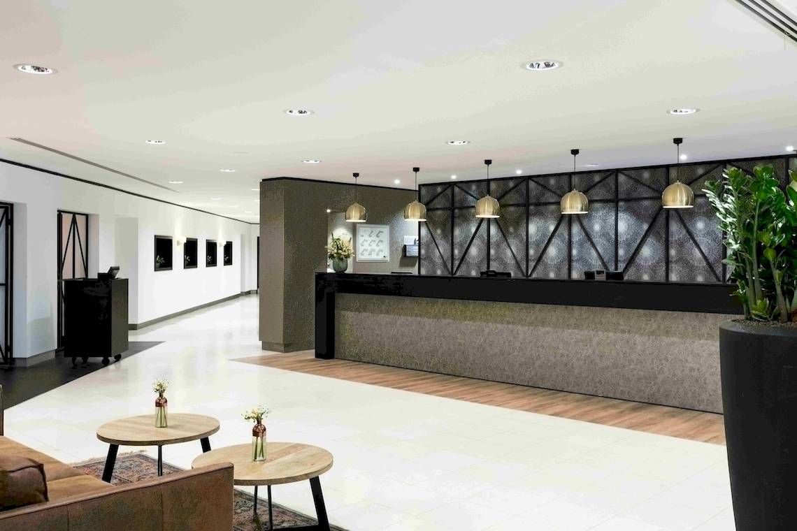 Rezeption des NH Amsterdam Centre Hotels mit modernem Design und Blumenarrangements.