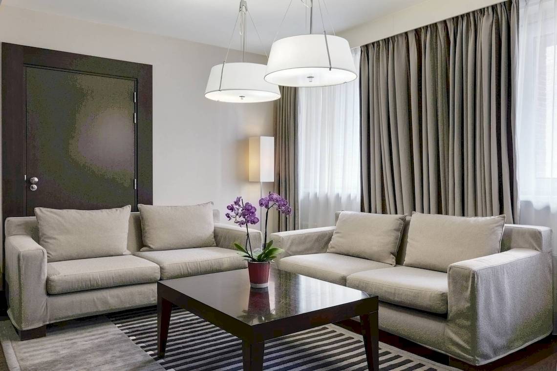 Wohnzimmer im NH Amsterdam Centre Hotel mit zwei Sofas, einem Tisch und dekorativen Elementen.