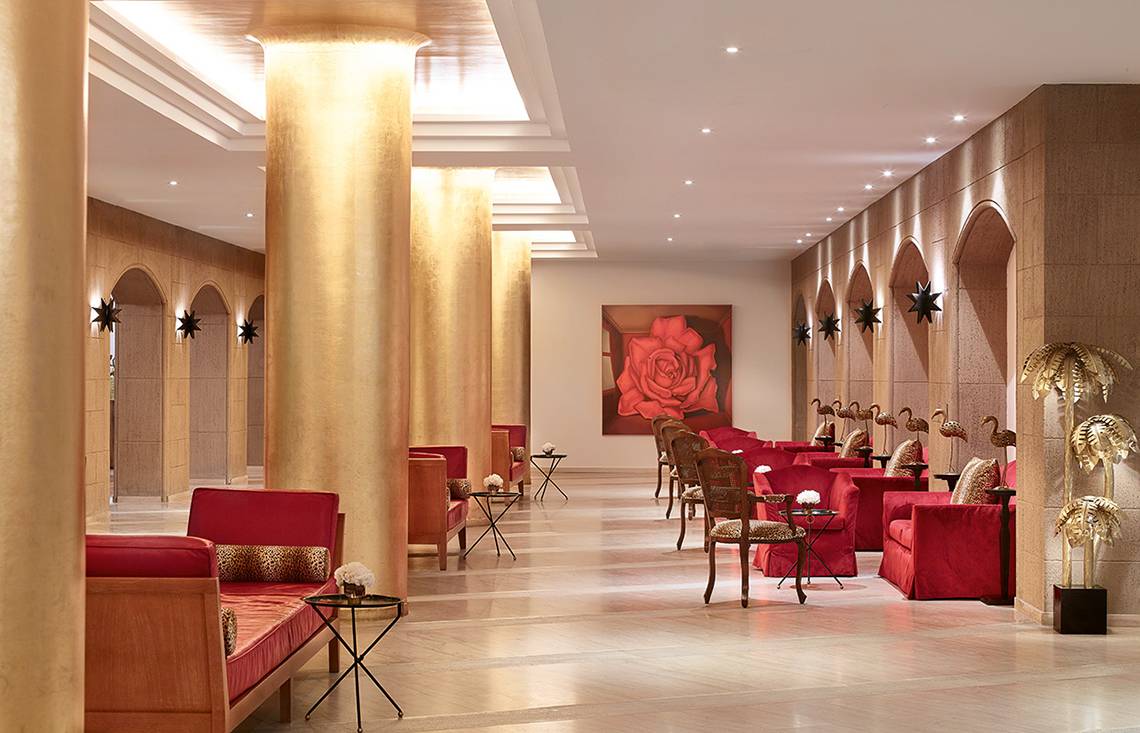 Lobby des Grecotel Lux Me Dama Dama Hotels mit roten Möbeln und einer großen roten Rose auf der Wand.