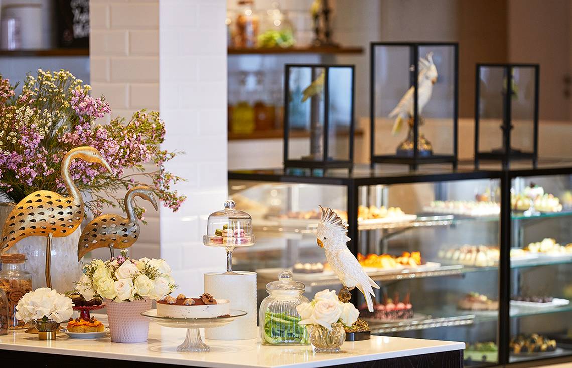 Empfangsbereich des Grecotel Lux Me Dama Dama Hotel mit Blumen, Figuren und Kuchen