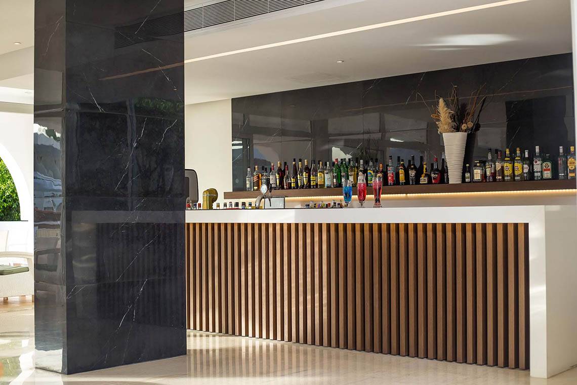 Die Bar des Niriides Beach Hotels mit vielen Flaschen und einer großen Marmorsäule.