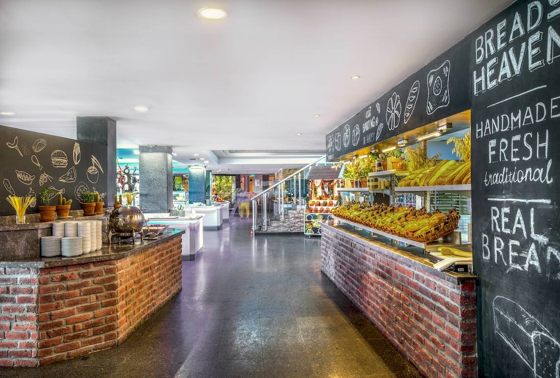 Innenansicht des Restaurants im Asteria Family Resort Belek mit rustikalem Design und Speisenbuffet.
