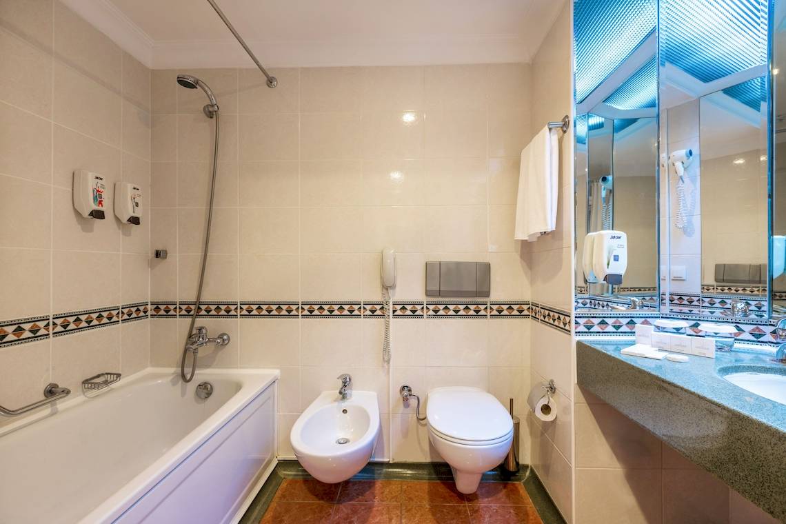 Ein Badezimmer mit Badewanne, Bidet und Toilette, Spiegel und Handtuchhalter.