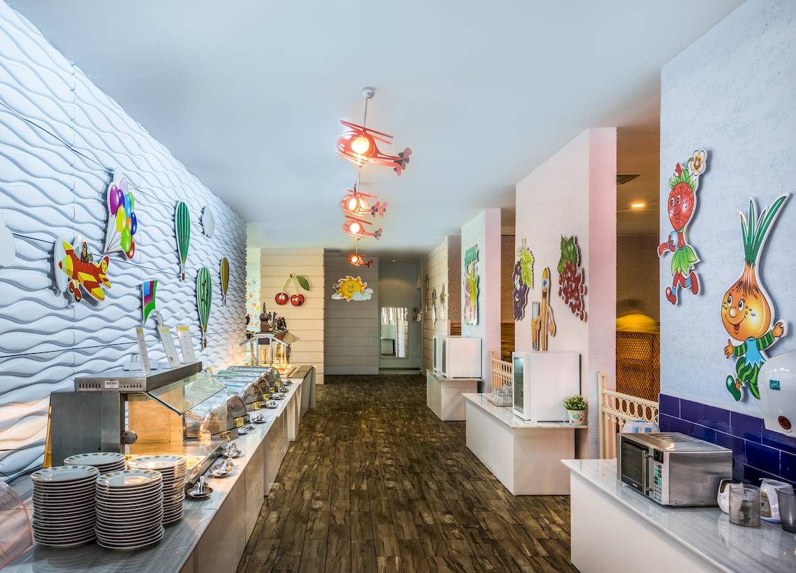 Innenbereich des Restaurants im Asteria Family Resort Belek mit farbenfrohen Wanddekorationen und Holzboden.