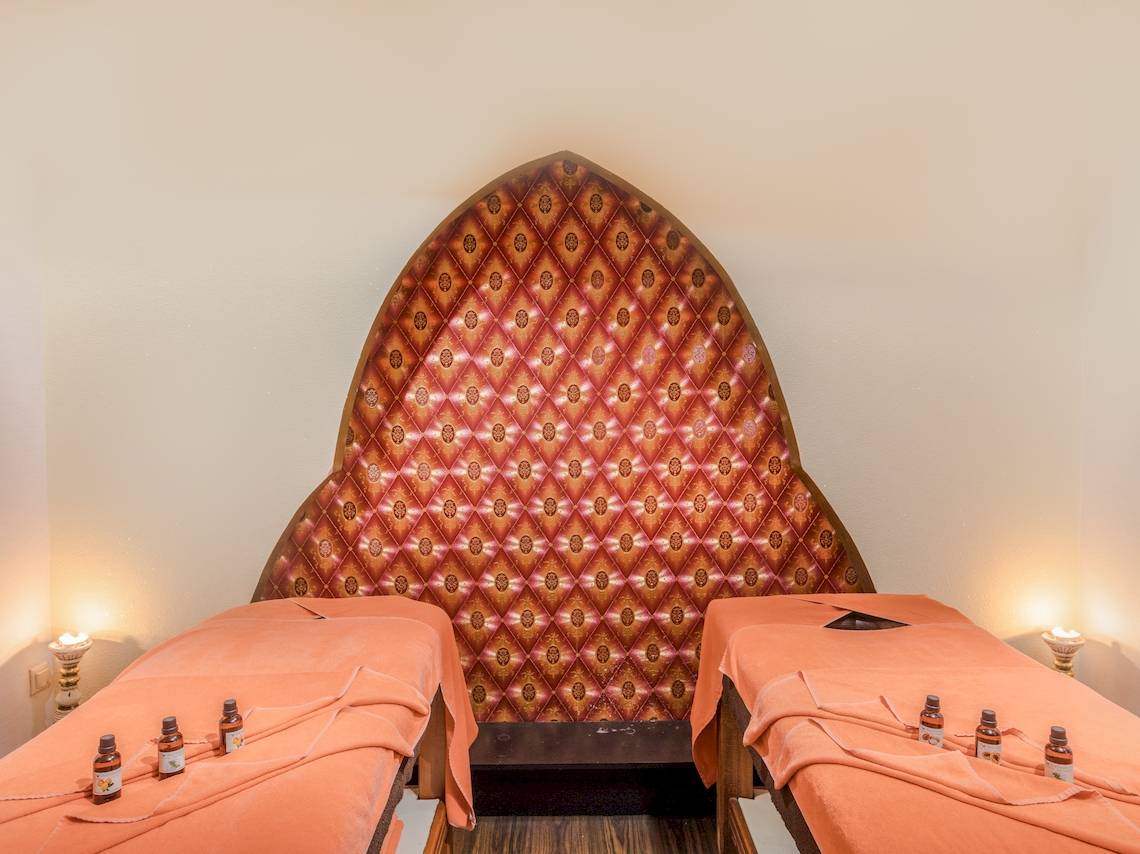 Behandlungsraum im Asteria Family Resort Belek mit zwei orangefarbenen Betten und einer aufwendigen Wand.