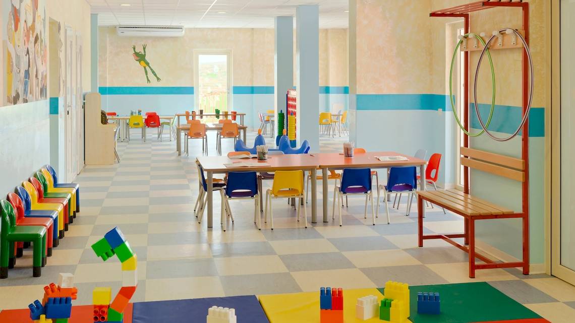 Kinderzimmer im VOI Praia De Chaves Resort mit bunten Stühlen und Tischen auf gemustertem Boden.