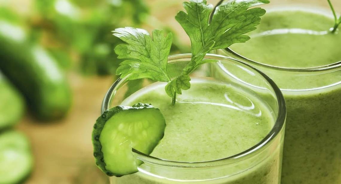 Zwei Gläser mit grünem Smoothie und Gurke, das Hotel Anantara Rasananda Koh Phangan Villas im Hintergrund