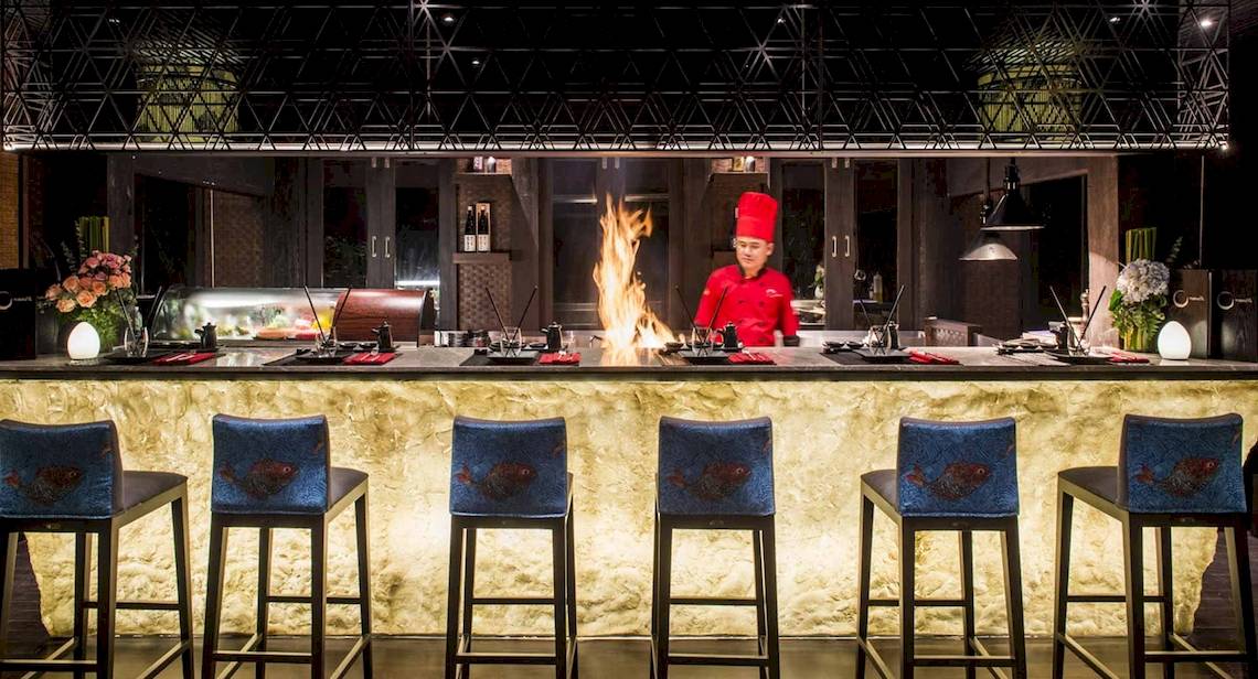 Koch im Restaurant der Anantara Rasananda Koh Phangan Villas mit einem großen Feuer.