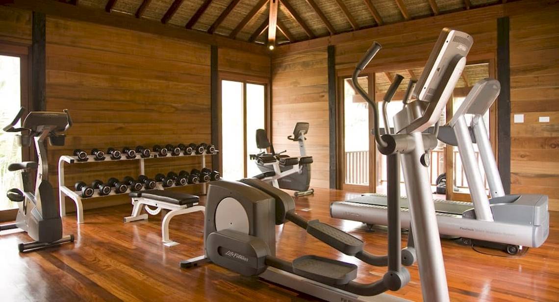 Fitnesscenter im Anantara Rasananda Koh Phangan Villas mit verschiedenen Geräten und Hanteln.