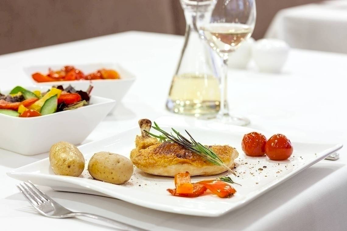 Ein Gericht im NH Hamburg Altona mit Hähnchen, Kartoffeln, Gemüse und Wein.