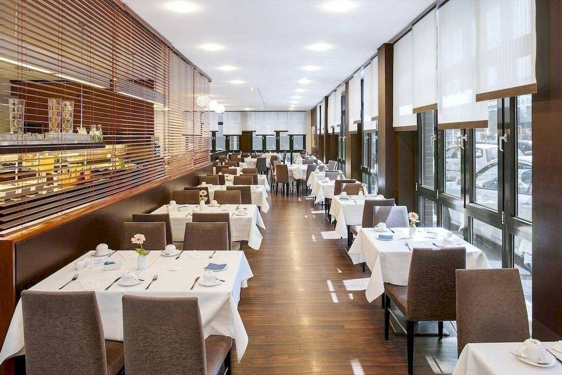 Innenansicht des Restaurants im NH Hamburg Altona mit gedeckten Tischen und Stühlen.