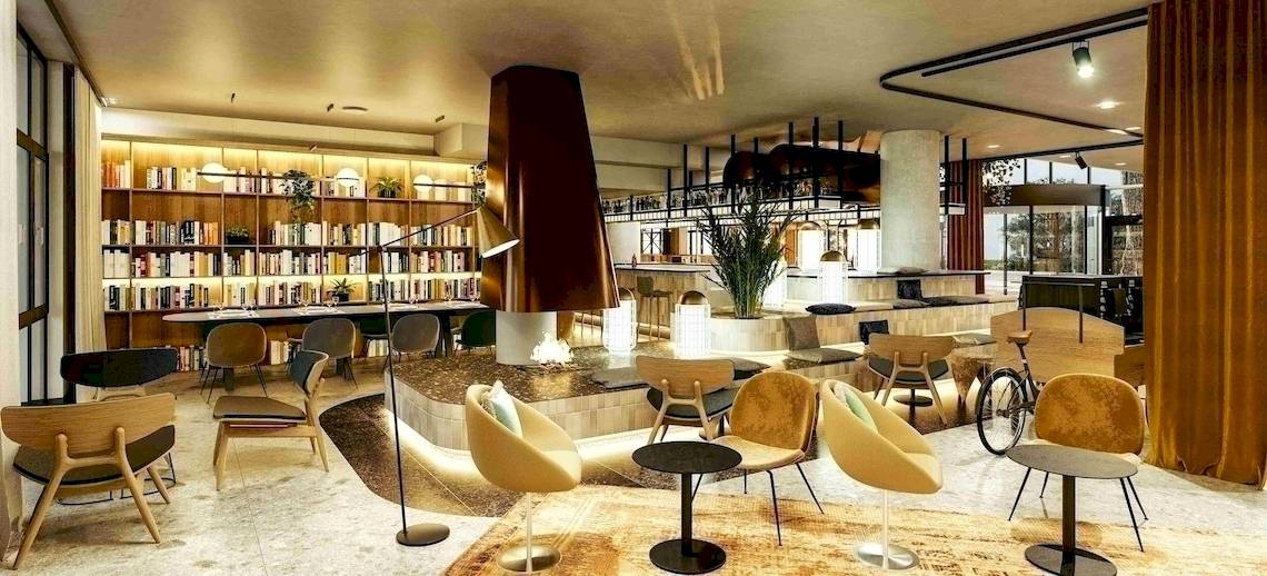 Lobby des NH Hamburg Altona Hotels mit Bücherregal, Sitzbereichen und Dekorationspflanzen.
