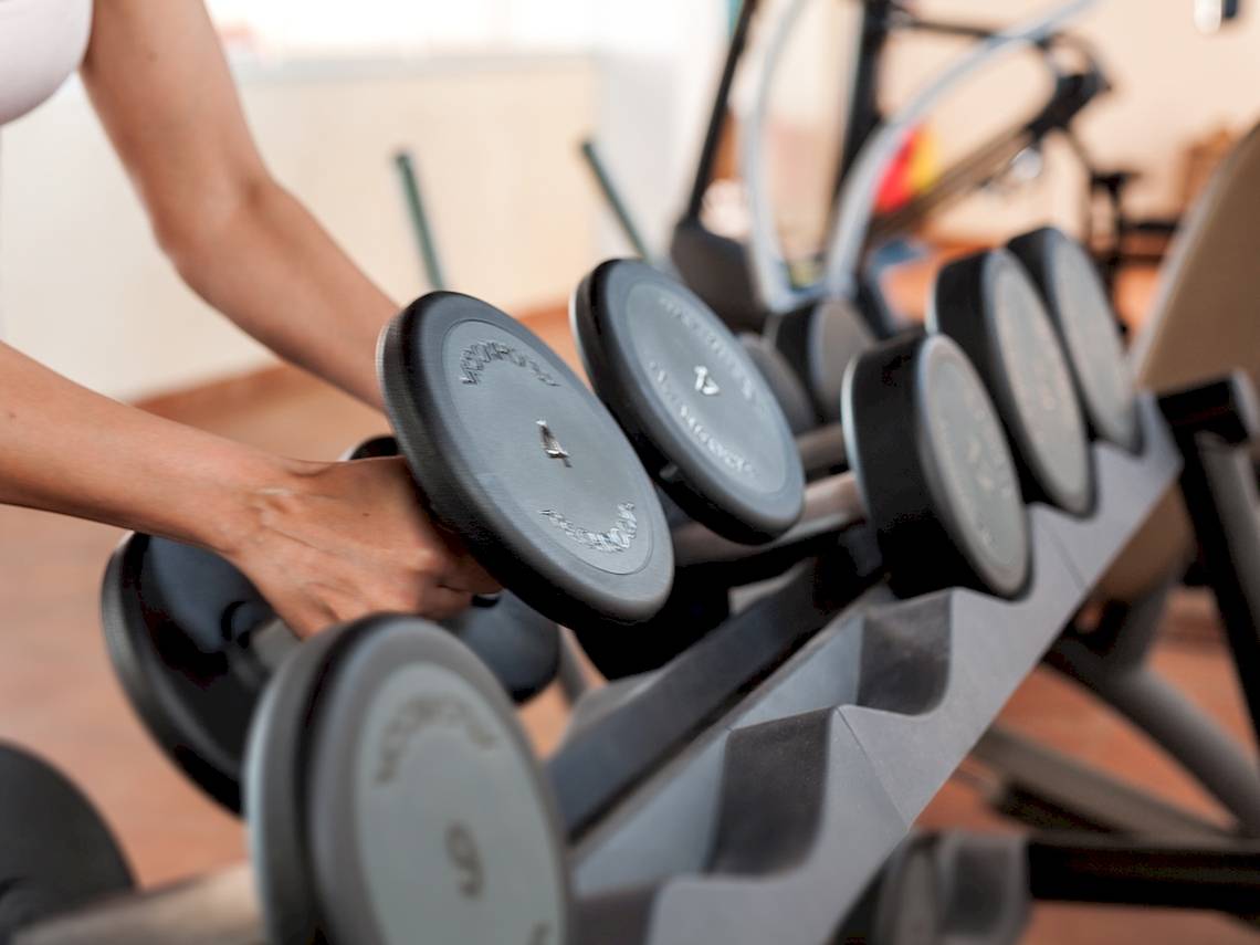 Eine Person hebt eine Hantel in einem Fitnessstudio.