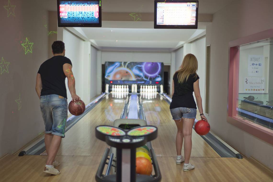 Zwei Personen, ein Mann und eine Frau, stehen in einer Bowlingbahn des Aydinbey Kings Palace & Spa.