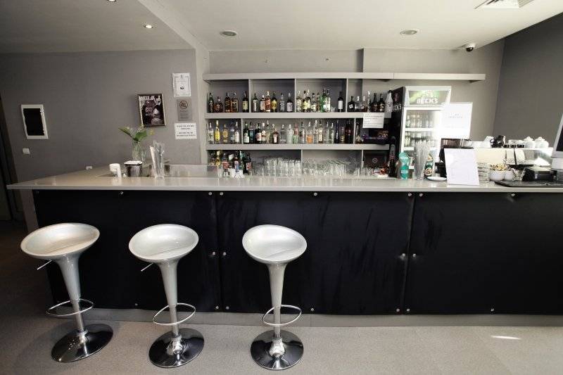 Die Bar im Gladiola Star Hotel mit Barhockern und einer Theke voller Getränke.