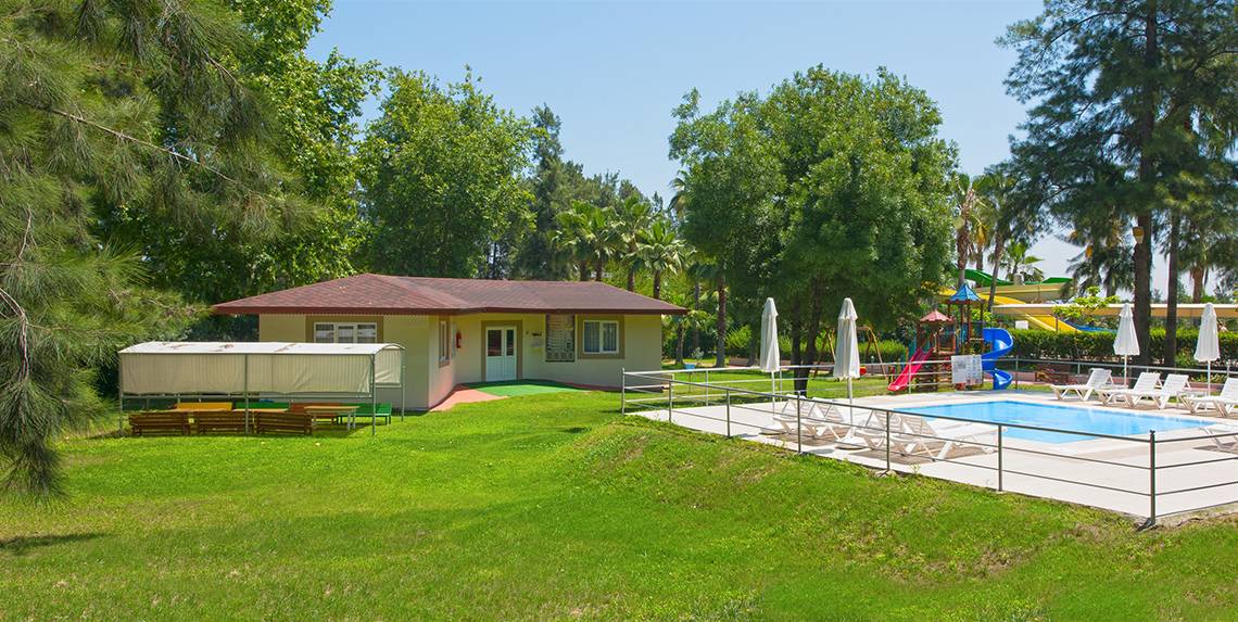 Außenbereich des Club Hotel Sidelya mit Pool, Liegestühlen und Spielgeräten.