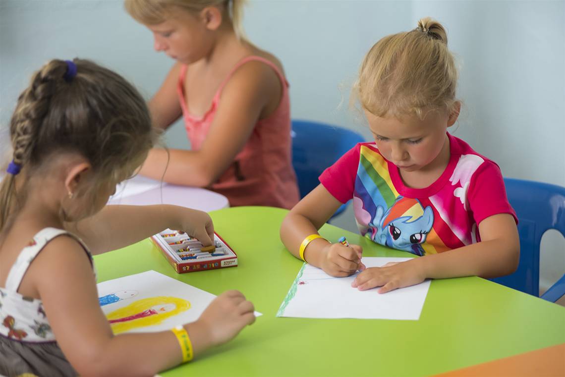 Kinder im Club Hotel Sidelya zeichnen an einem grünen Tisch.