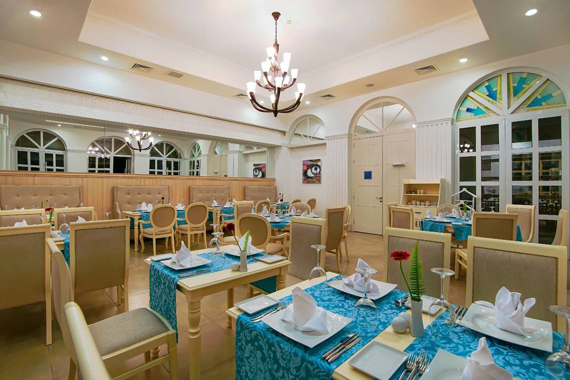 Innenansicht des Restaurants im Baia Lara Hotel mit gedeckten Tischen und Stühlen.