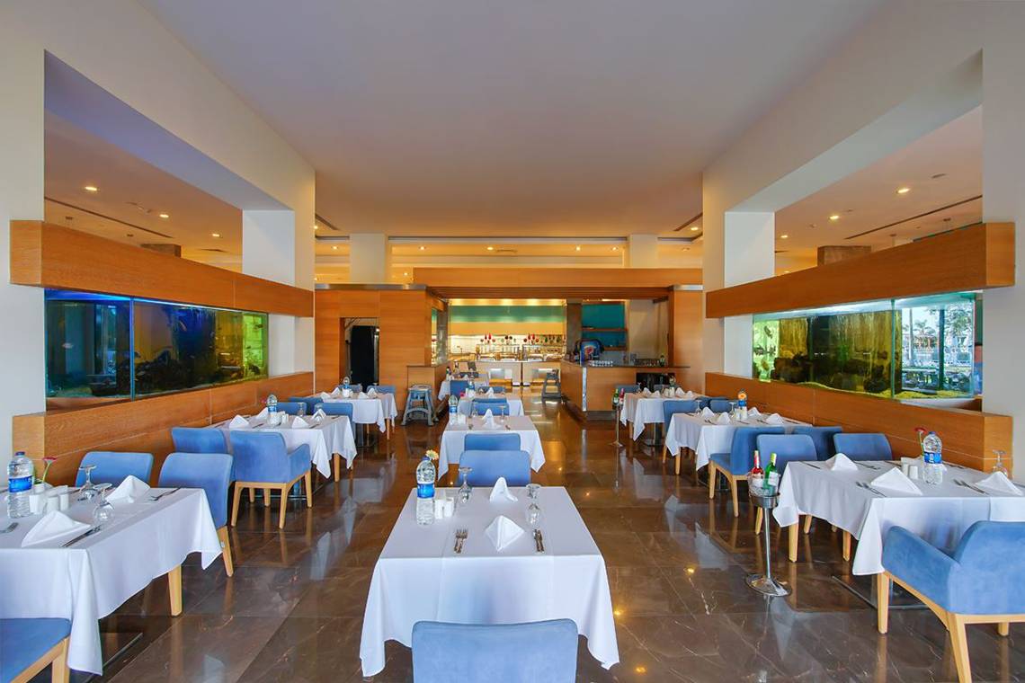 Innenansicht des Restaurants im Baia Lara Hotel mit blauen Stühlen und Tischen.