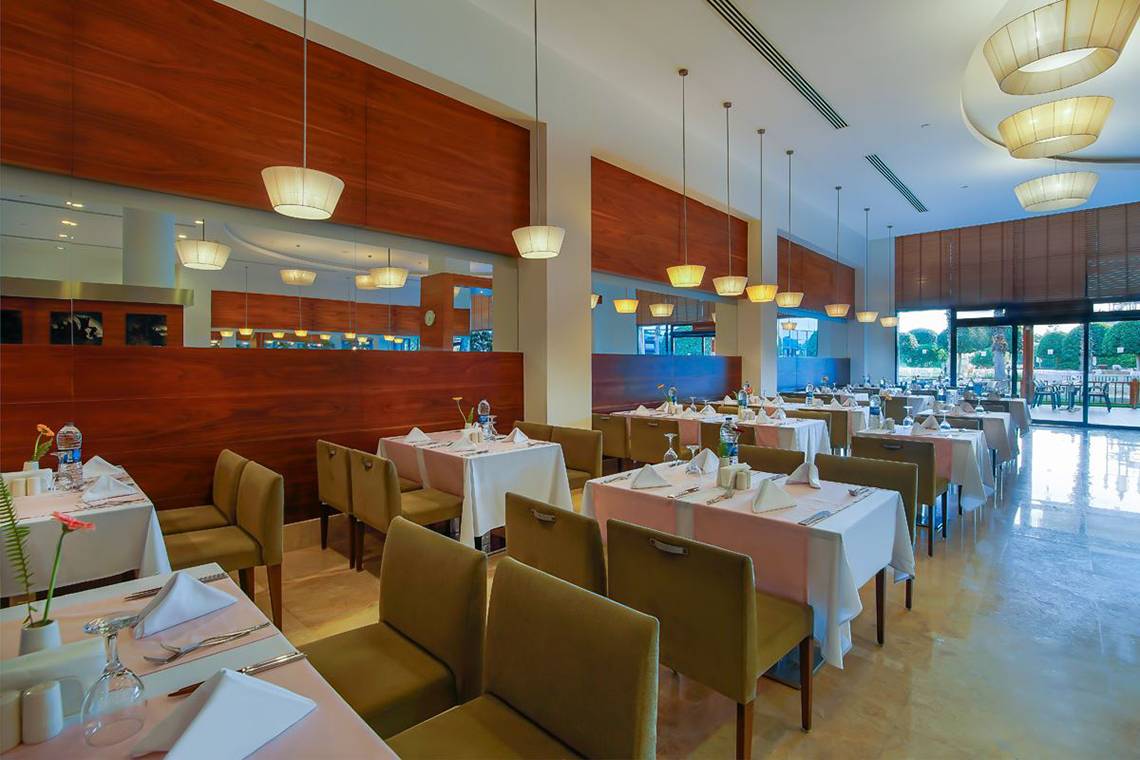 Innenansicht des Restaurants im Baia Lara Hotel mit gedeckten Tischen und Holzwänden.
