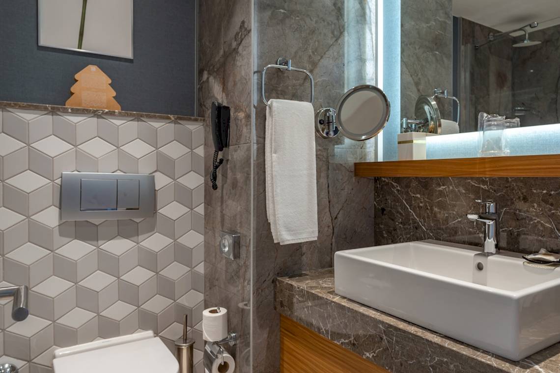 Ein elegantes Badezimmer im Baia Lara Hotel mit einer weißen Toilette, einem Waschbecken und einer Dusche.