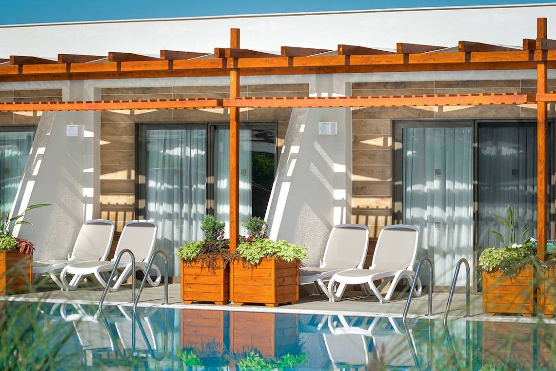 Außenpool und Terrasse des Baia Lara Hotels mit weißen Sonnenliegen und Holzpergolen