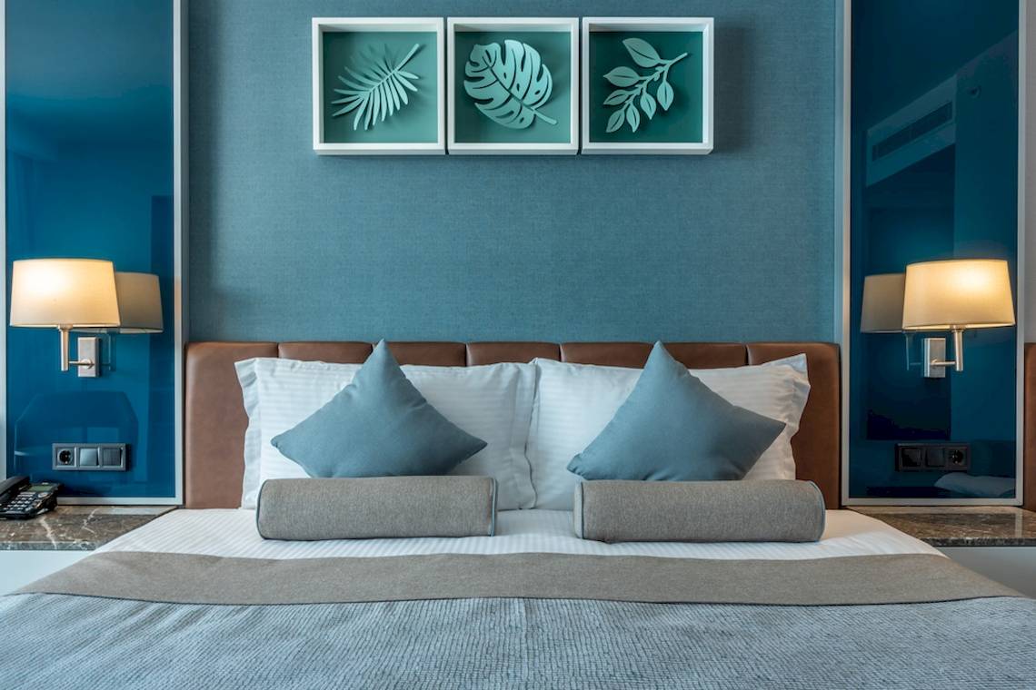 Hotel Baia Lara Schlafzimmer mit blauen Wand und modernem Bett.