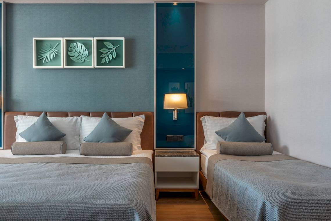 Doppelbett-Zimmer im Baia Lara Hotel mit modernen Wanddekorationen und Nachttischen.