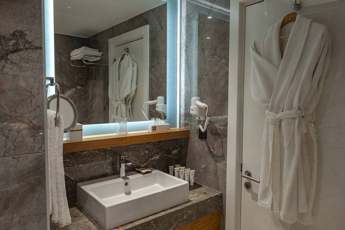 Badezimmer im Baia Lara Hotel mit Waschbecken, Spiegel und Handtüchern.