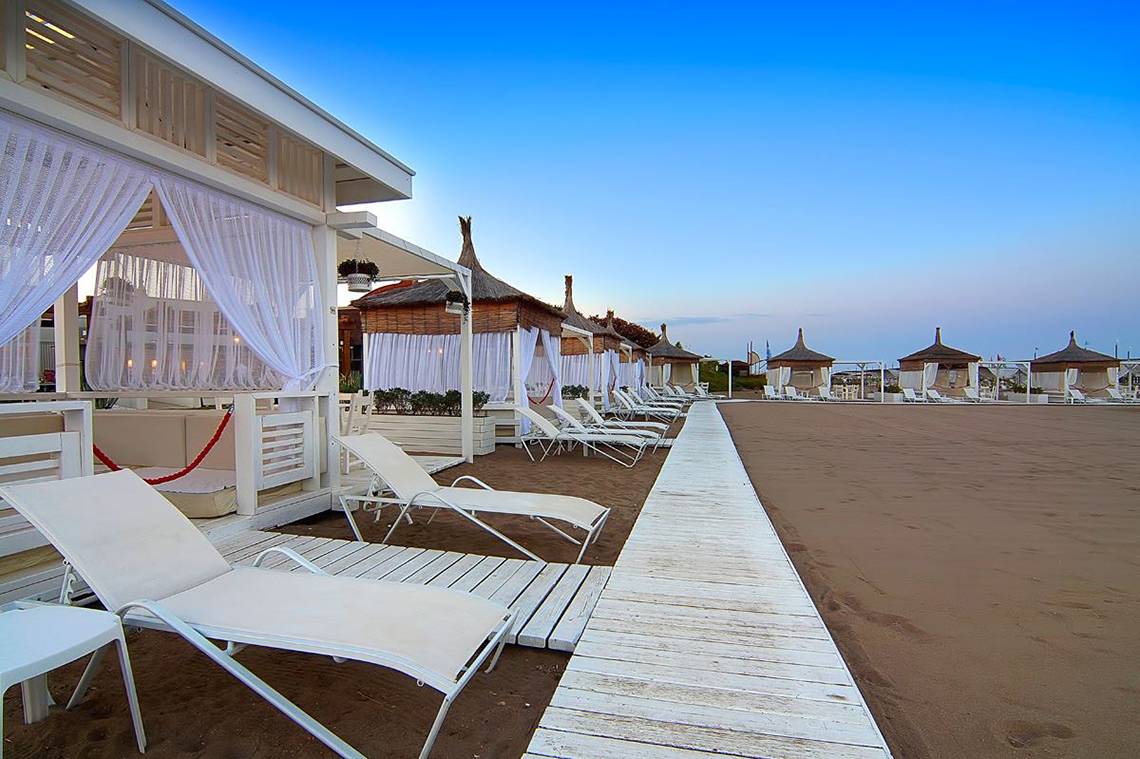 Außenbereich des Baia Lara Hotels mit weißen Sonnenliegen und Pavillons am Strand