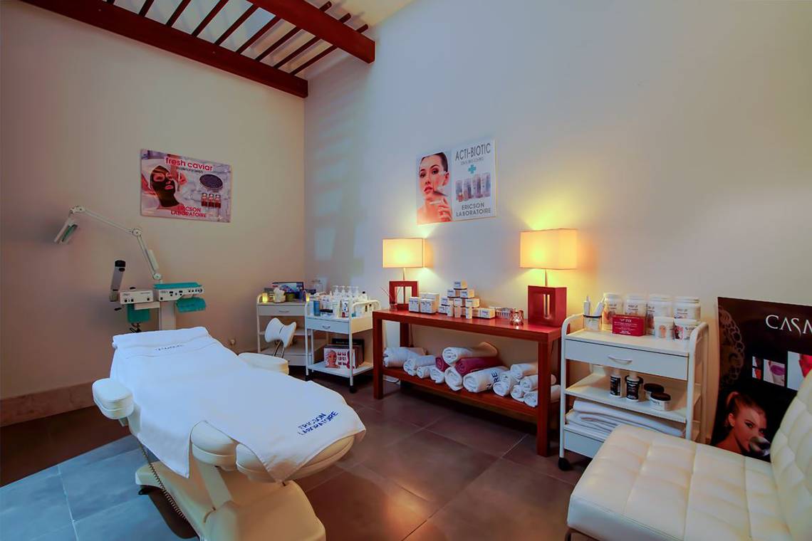 Kosmetikbehandlungsraum im Baia Lara Hotel mit Behandlungsliege, Lampen und Produkten.