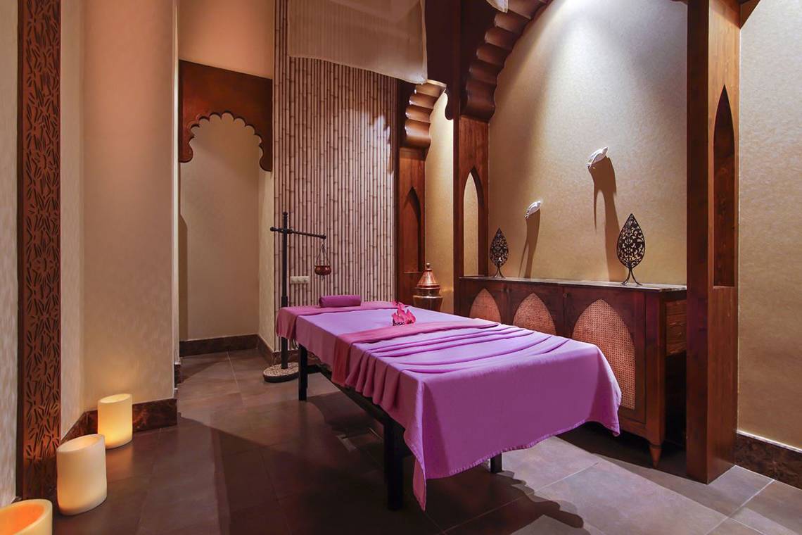 Massageraum im Baia Lara Hotel mit einem violetten Massagetisch und dekorativen Elementen.