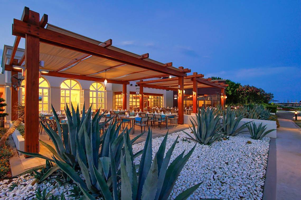 Außenbereich des Baia Lara Hotels mit beleuchteter Pergola und gedeckten Tischen.
