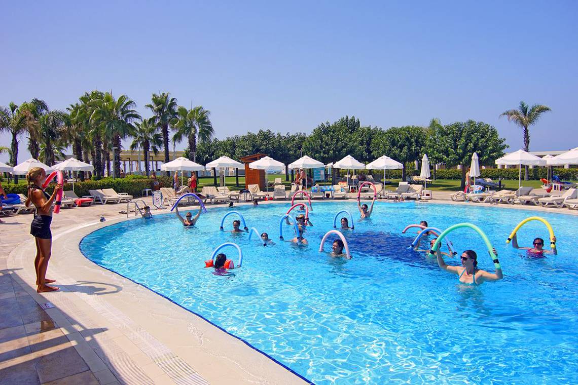 Aerobics-Übung im Pool des Baia Lara Hotels mit Teilnehmern und Palmen im Hintergrund.