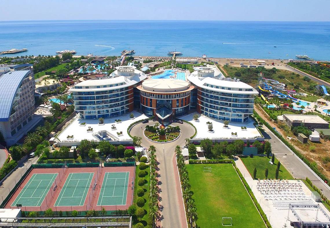 Luftaufnahme des Baia Lara Hotels mit Tennisplätzen, Meer und Wasserrutschen.