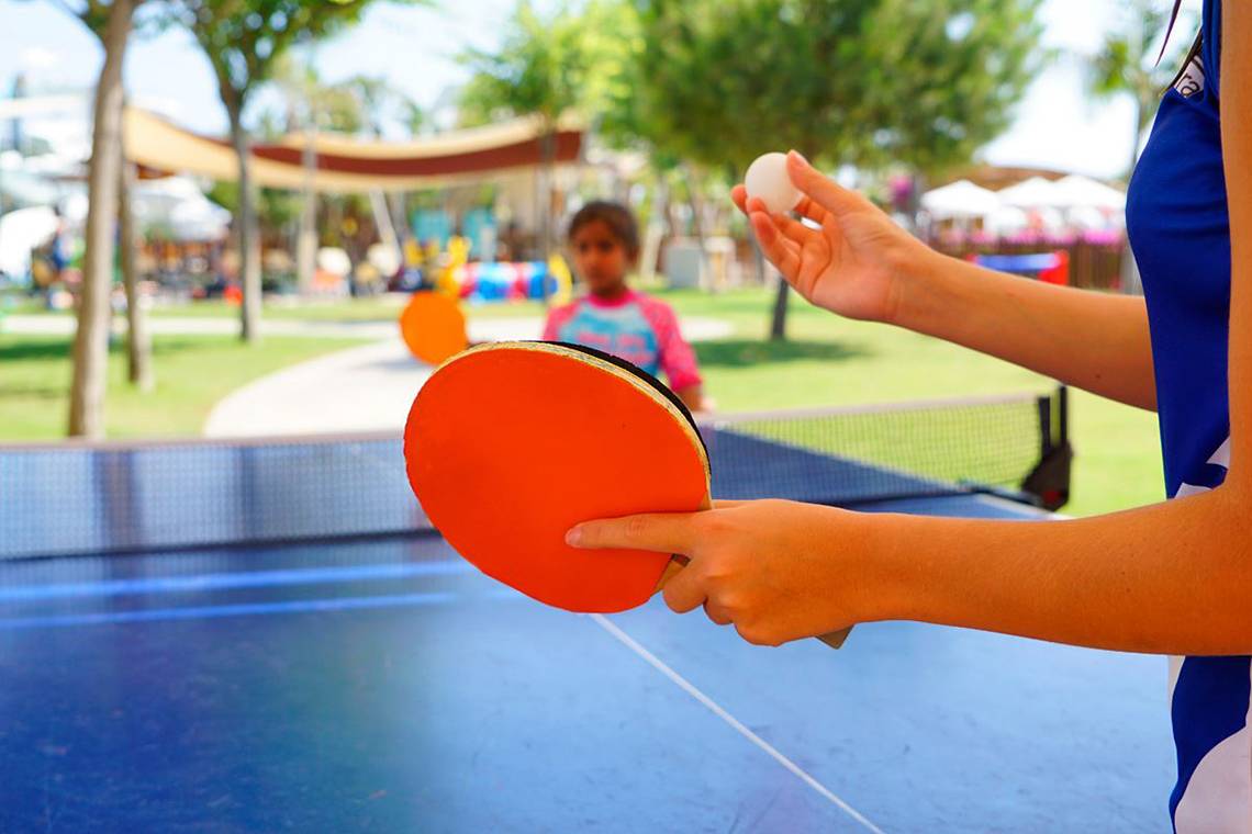 Eine Person spielt Tischtennis im Freien im Baia Lara Hotel, während eine andere Person den Ball hält.