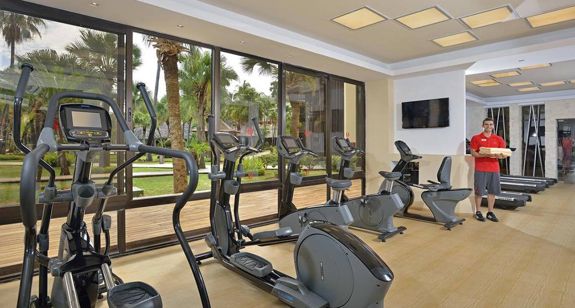 Fitnessstudio im Sol Palmeras Hotel mit Geräten und einem Mann, der etwas trägt.