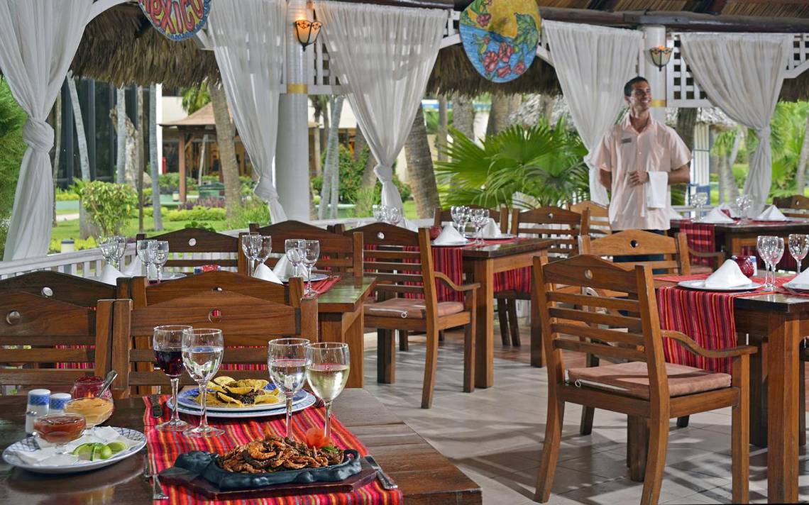Restaurant des Sol Palmeras Hotels mit gedeckten Tischen und einem Kellner, der lächelt.