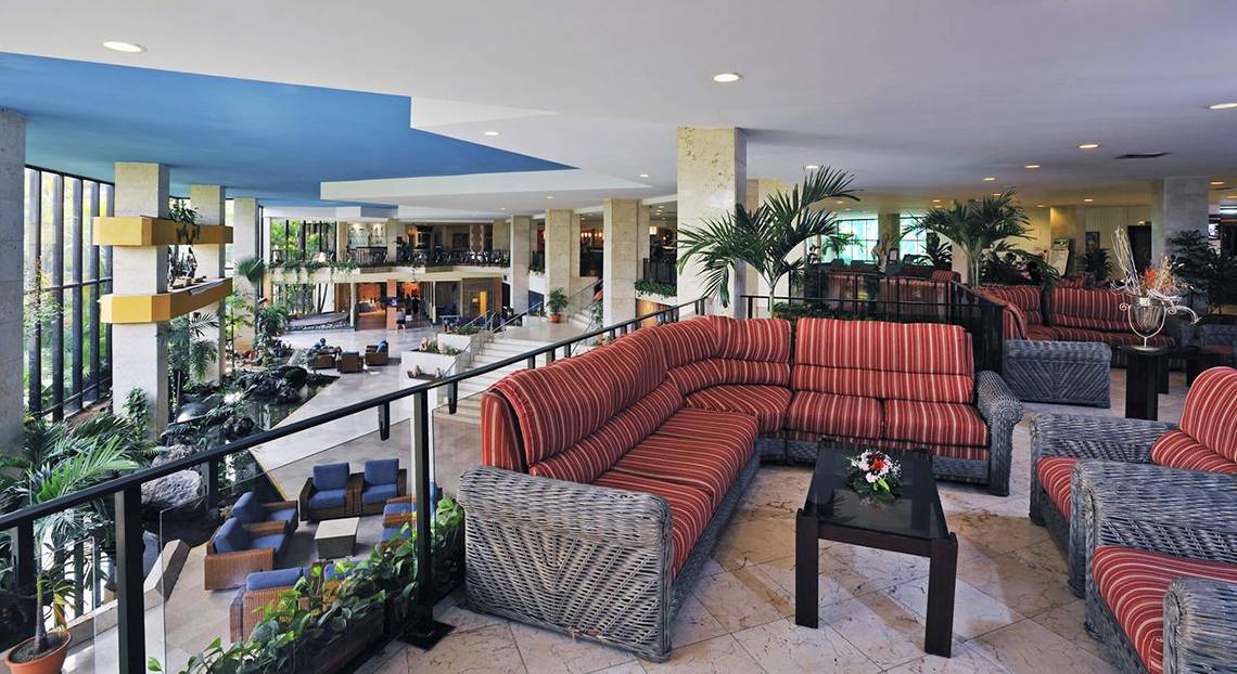 Lobby des Sol Palmeras Hotels mit roten Sofas, Tischen und Pflanzen.
