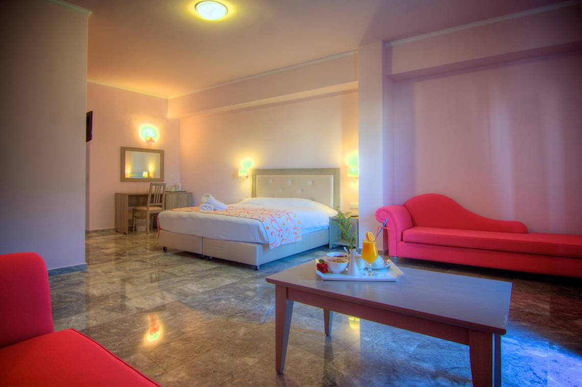 Das Schlafzimmer im Solimar Dias Hotel mit einem Bett, einem Schreibtisch, einem roten Sofa und einem Tisch mit Getränken.
