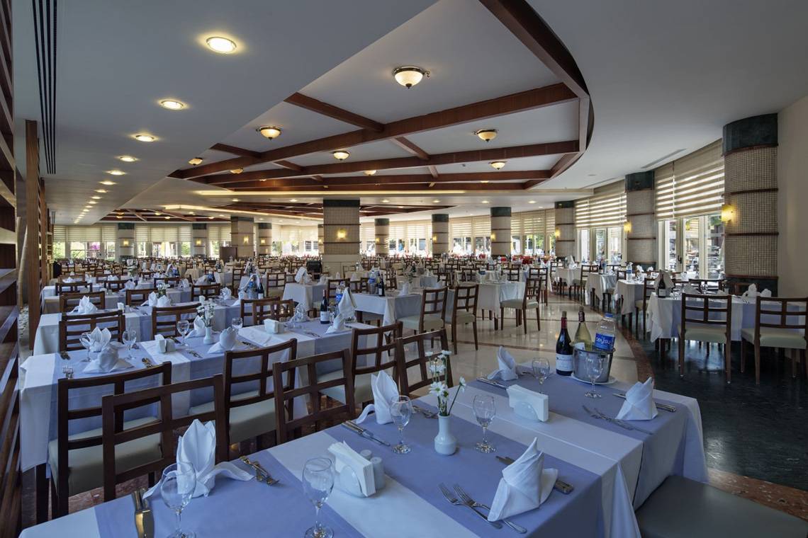Innenansicht des Restaurants im Liberty Hotels Lara mit vielen gedeckten Tischen und Stühlen.