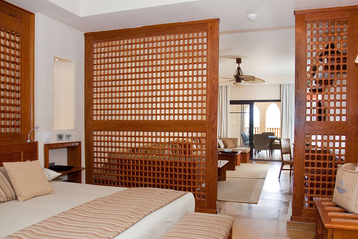 Schlafzimmer im Grand Waterworld Makadi Hotel mit Holzelementen und modernen Möbeln.